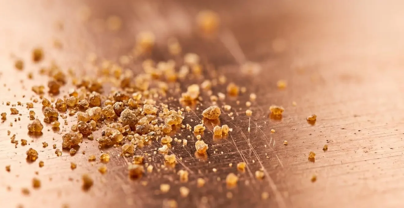 Close-up view of rosin particles on copper plate surface showing granular texture for aquatint printmaking technique