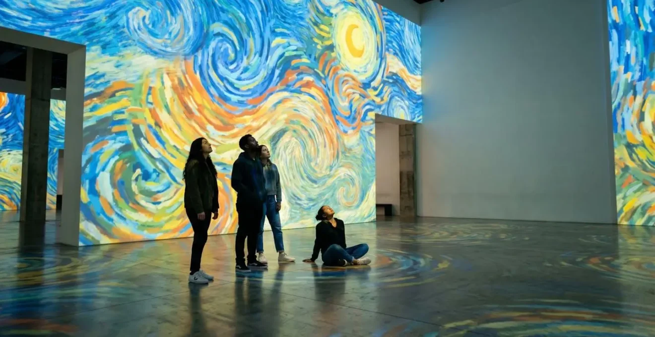 Young visitors interacting with floor-to-ceiling immersive art projections in a contemporary gallery space